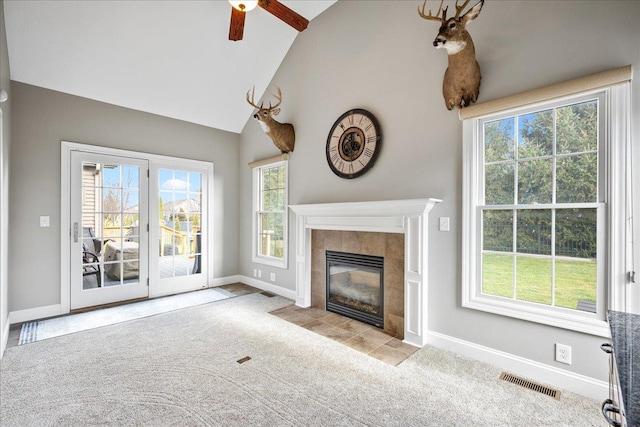 unfurnished living room featuring ceiling fan, light carpet, a tile fireplace, and vaulted ceiling