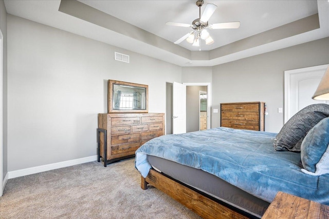 carpeted bedroom with a tray ceiling and ceiling fan