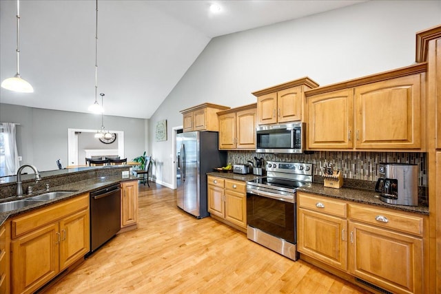 kitchen with pendant lighting, backsplash, sink, dark stone countertops, and appliances with stainless steel finishes