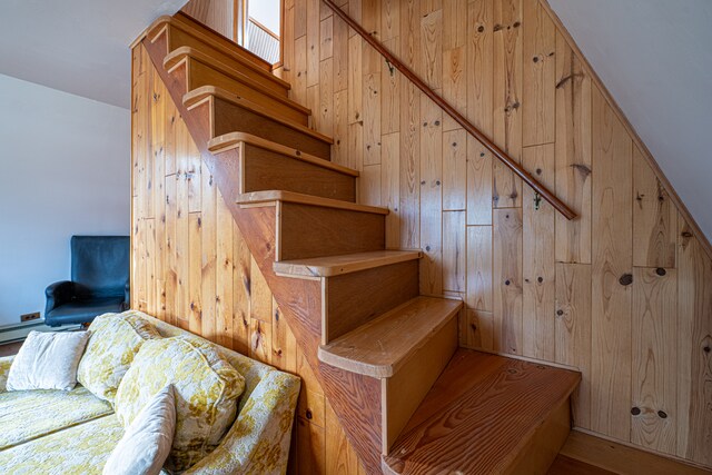 staircase featuring wood-type flooring and wooden walls