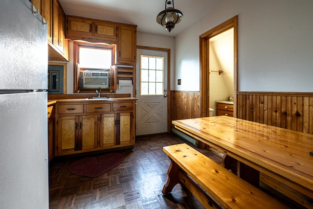 kitchen featuring dark parquet floors, cooling unit, wooden walls, white refrigerator, and hanging light fixtures