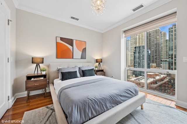 bedroom with visible vents, wood finished floors, and ornamental molding