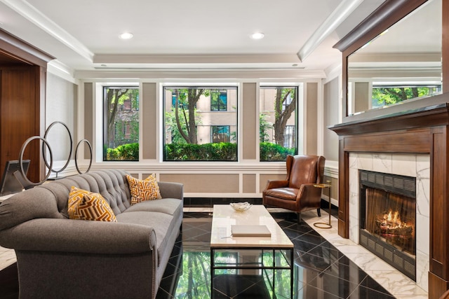 interior space featuring a healthy amount of sunlight, a tray ceiling, a decorative wall, and a tiled fireplace