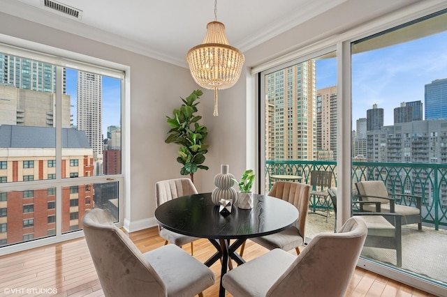 dining space with visible vents, crown molding, a city view, and wood finished floors