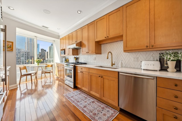 kitchen with a city view, stainless steel appliances, visible vents, a sink, and under cabinet range hood