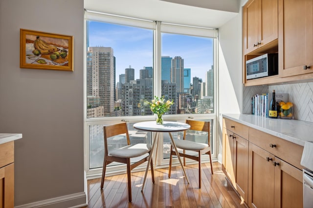 dining room featuring light wood-style flooring, a view of city, and baseboards