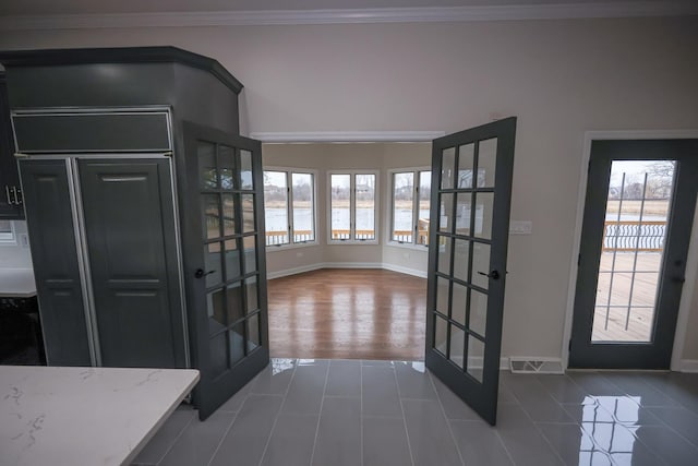 foyer featuring dark hardwood / wood-style flooring, a wealth of natural light, french doors, and ornamental molding