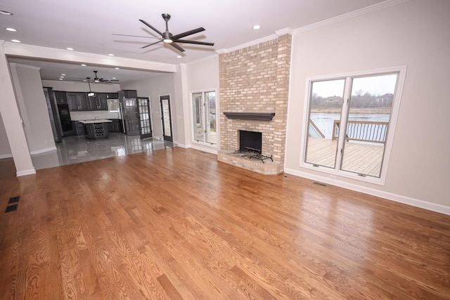 unfurnished living room with hardwood / wood-style floors, a fireplace, and crown molding