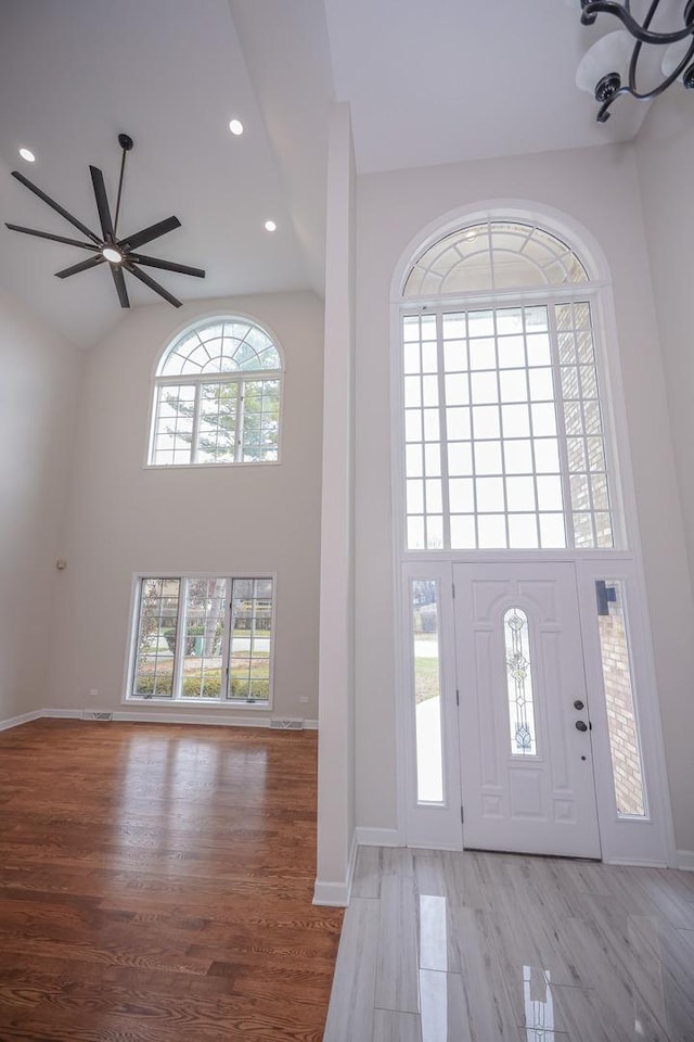 foyer with ceiling fan, a high ceiling, and light wood-type flooring