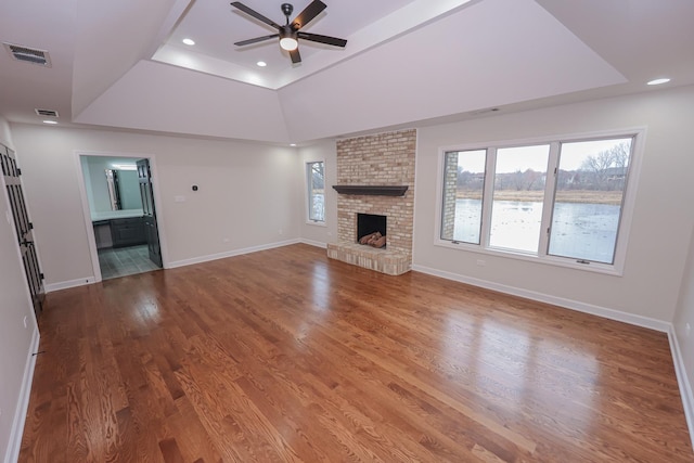 unfurnished living room with a fireplace, wood-type flooring, a raised ceiling, and ceiling fan