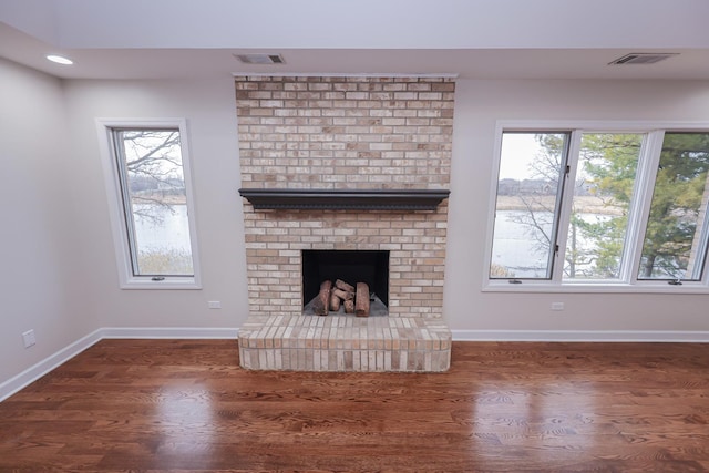 unfurnished living room featuring dark hardwood / wood-style flooring and a brick fireplace