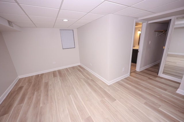 basement featuring a drop ceiling and light hardwood / wood-style flooring