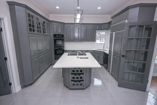 kitchen featuring gray cabinets, crown molding, a center island with sink, and black appliances