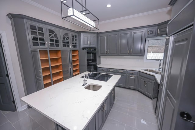 kitchen featuring gray cabinetry, double oven, pendant lighting, a center island with sink, and stovetop