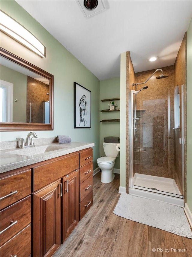 bathroom featuring hardwood / wood-style floors, vanity, toilet, and an enclosed shower