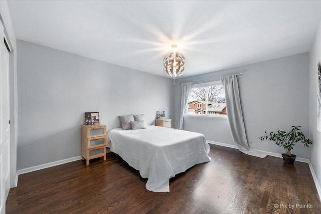 bedroom with dark wood-type flooring and an inviting chandelier