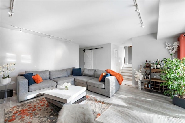 living room featuring a barn door, rail lighting, and light hardwood / wood-style floors