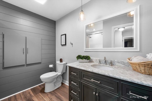 bathroom with wood-type flooring, vanity, toilet, and wooden walls