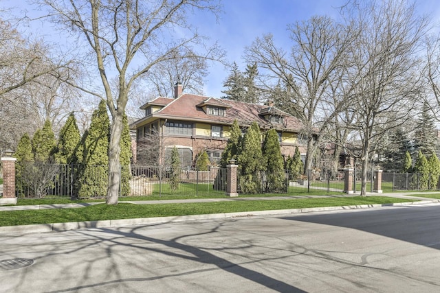 view of front of property featuring brick siding, a fenced front yard, and a chimney