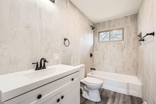 full bathroom featuring toilet, hardwood / wood-style flooring, vanity, tile walls, and tiled shower / bath