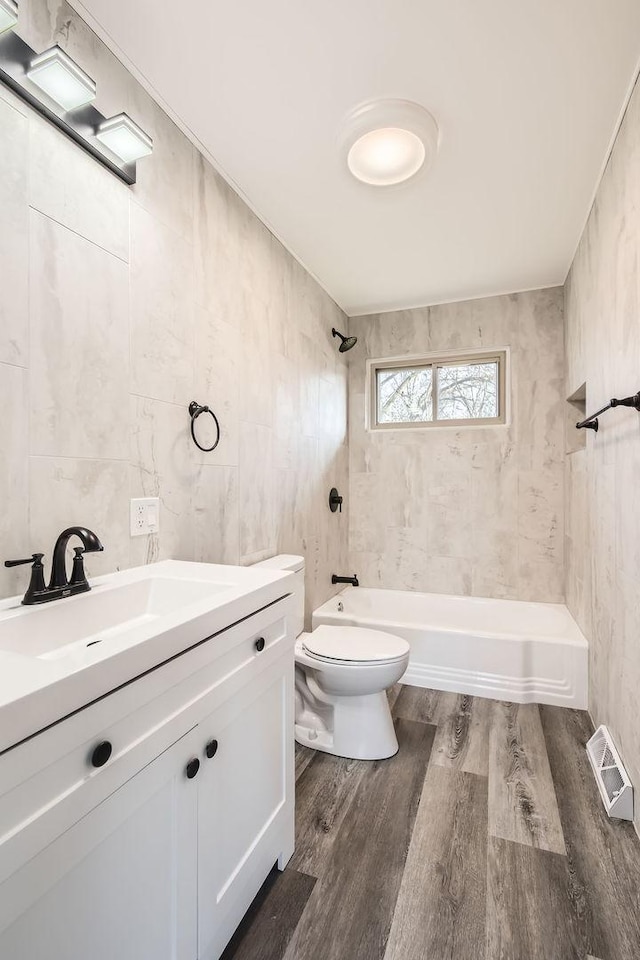 full bathroom featuring vanity, tiled shower / bath combo, tile walls, hardwood / wood-style floors, and toilet