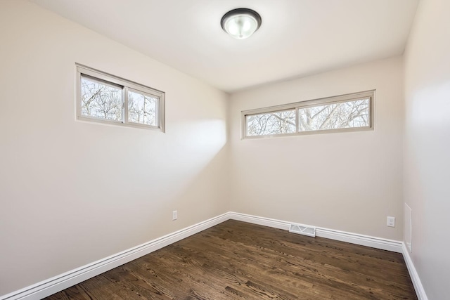 empty room with dark hardwood / wood-style floors and plenty of natural light