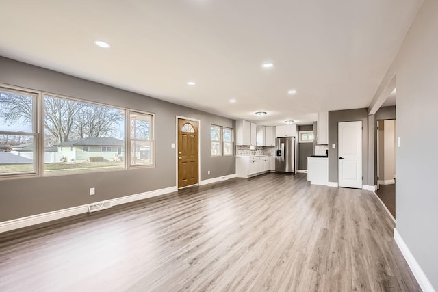 unfurnished living room with sink and light hardwood / wood-style flooring