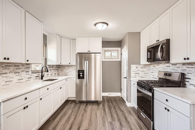 kitchen featuring sink, white cabinets, light hardwood / wood-style floors, and appliances with stainless steel finishes