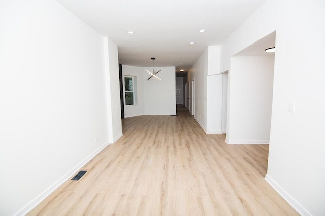 corridor featuring a notable chandelier and light wood-type flooring