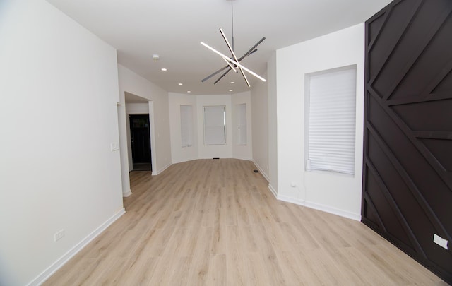 unfurnished room with an inviting chandelier and light hardwood / wood-style flooring