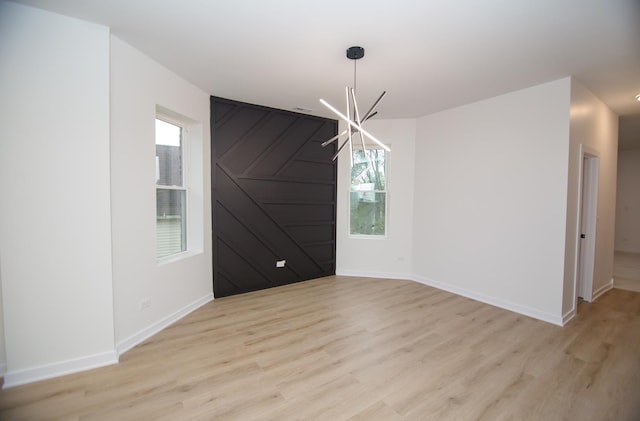 unfurnished dining area featuring plenty of natural light, an inviting chandelier, and light hardwood / wood-style flooring