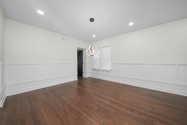 empty room featuring dark hardwood / wood-style flooring and an inviting chandelier