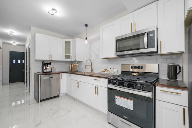 kitchen with backsplash, white cabinetry, sink, and stainless steel appliances