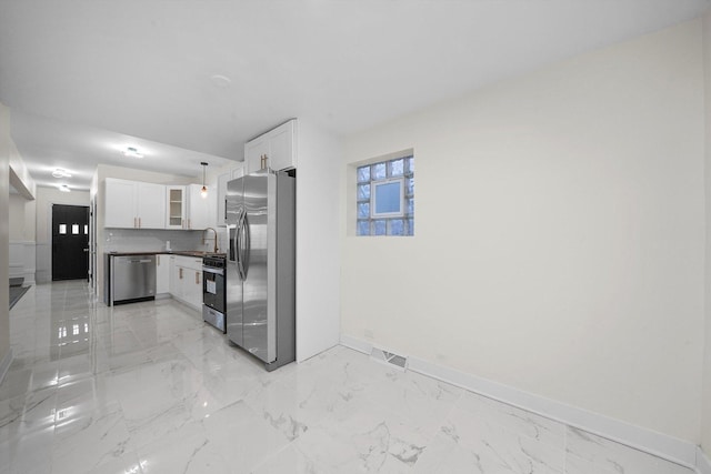 kitchen featuring backsplash, sink, decorative light fixtures, white cabinetry, and stainless steel appliances