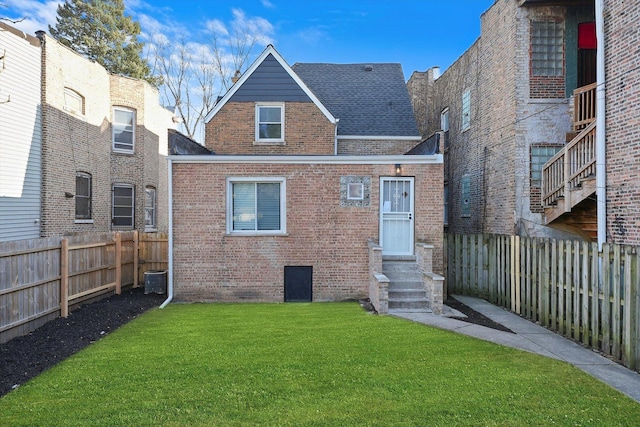 rear view of property featuring a lawn and cooling unit