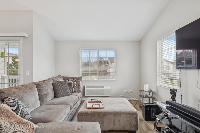 living room featuring lofted ceiling, light hardwood / wood-style flooring, and a wall mounted air conditioner