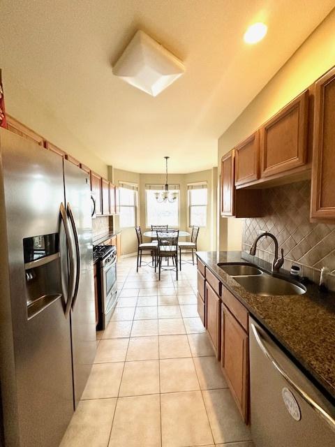 kitchen featuring sink, stainless steel appliances, tasteful backsplash, light tile patterned flooring, and decorative light fixtures