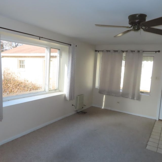 carpeted spare room featuring radiator, plenty of natural light, and ceiling fan