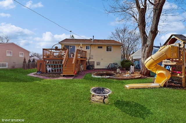 rear view of house with a playground, a yard, a fire pit, and a deck