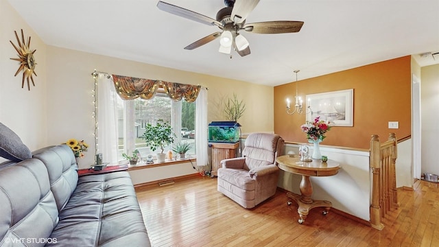 living area with light hardwood / wood-style flooring and ceiling fan with notable chandelier