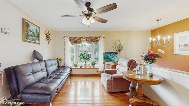 living area featuring ceiling fan with notable chandelier and light hardwood / wood-style flooring