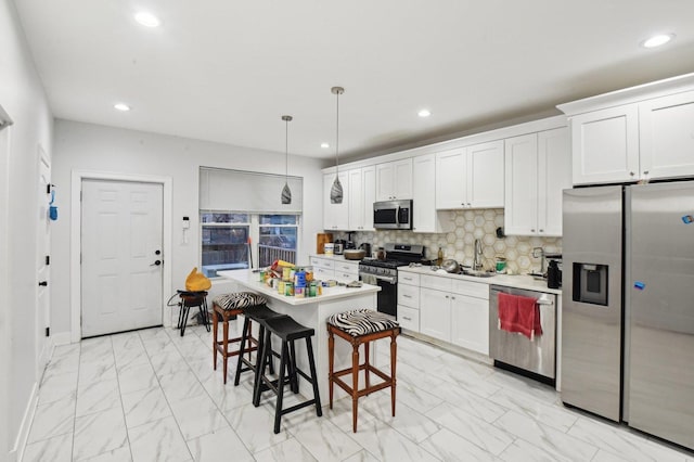 kitchen with stainless steel appliances, pendant lighting, a center island, white cabinetry, and a breakfast bar area