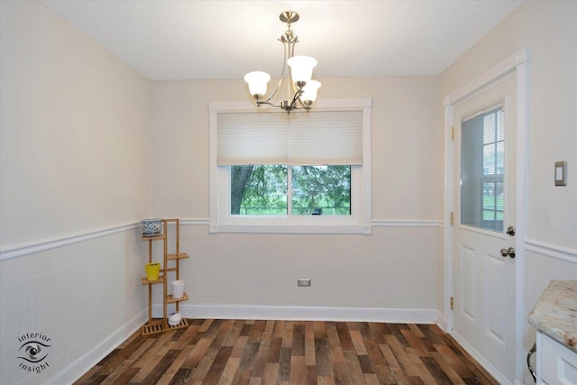 empty room with dark hardwood / wood-style flooring and a notable chandelier