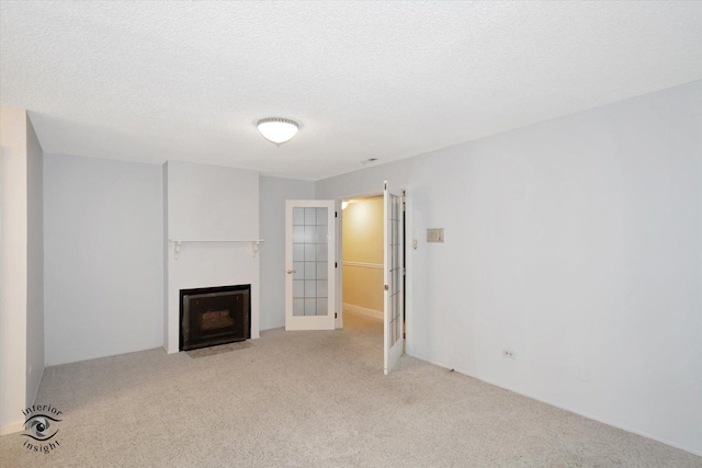 unfurnished living room with light carpet, french doors, and a textured ceiling