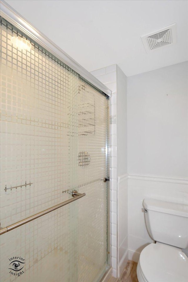 bathroom featuring toilet and a shower with shower door