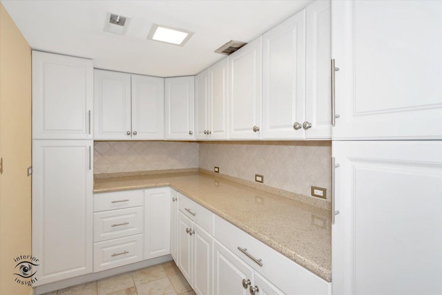 kitchen with light stone counters, tasteful backsplash, white cabinetry, and light tile patterned flooring