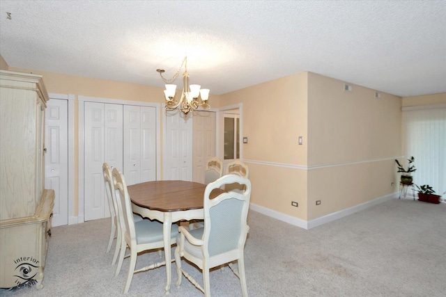 dining area featuring a textured ceiling, light colored carpet, and a notable chandelier