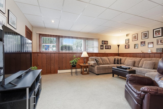 living room featuring wooden walls, a baseboard radiator, light carpet, and a drop ceiling