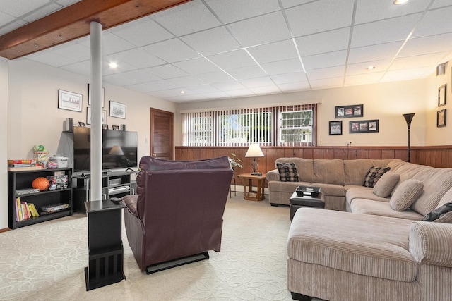 living room featuring light carpet, wood walls, and a drop ceiling