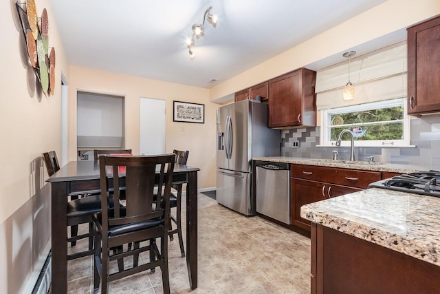 kitchen featuring hanging light fixtures, sink, tasteful backsplash, rail lighting, and stainless steel appliances